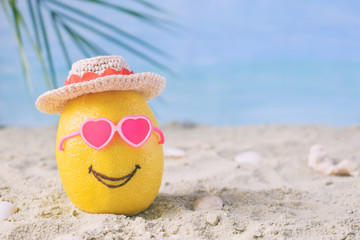 Creative minimal summer idea. Lemon citrus hipster in pink sunglasses and bamboo hat on sand. Tropical beach concept. Creative art. Fun party Mood. Copy space