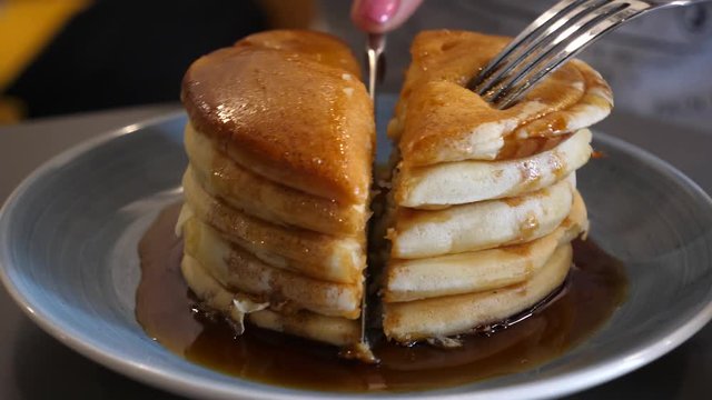 In Cafe slicing with knife on pieces eating a sweet pancake pie for the breakfast