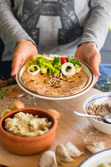 Woman hands holds garlic naan bread with butter, seeds and vegetables salad. Traditional Indian asian plain flatbread made with whole wheat flour. Raw vegan vegetarian healthy food