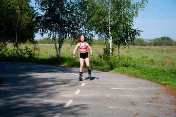 Roller skating woman in park rollerblading on inline skates. Beautiful woman learns to roller skate...