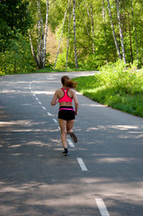 Beautiful smiling woman running in the park in the morning. Fitness girl running in the park. Running woman. Female Runner Jogging during Outdoor Workout in a Park. Beautiful fit Girl.