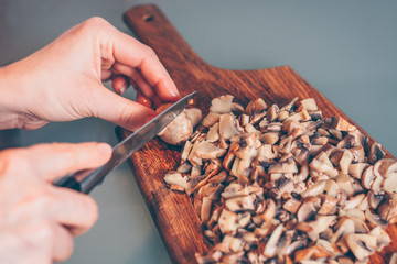 The cook cuts boiled mushrooms on a cutting board