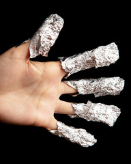 Fingers in foil in beauty salon on black background