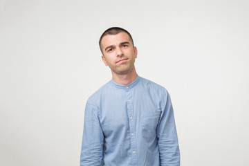 Close up of a doubtful young man in blue shirt. He is not sure what to do.