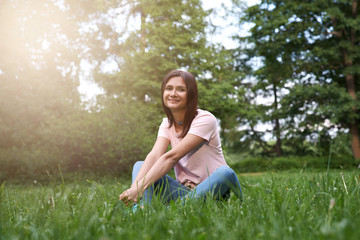 Naklejka na ściany i meble Girl in the grass. Beautiful young woman on the lawn. Siting in the grass, Happy woman. A warm summer day. Inspiration. Spring Beauty Girl. Happiness. Outdoors. Youth concept