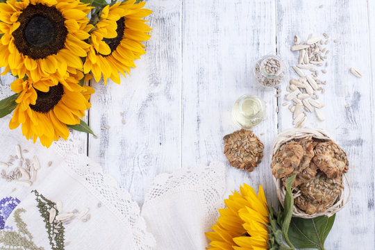 Sunflower oil and large yellow flowers. Oil in the bottle. Without peel of sunflower seeds and cookies. White wooden background. Vintage photo. Organic food. Copy space. Flat lay.
