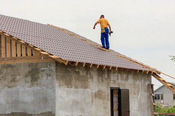 Man builds a roof on the house with a metal profile