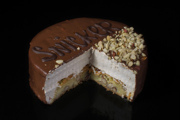 A piece of chocolate cake with hazelnut with white cream on a black background