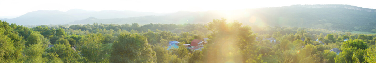 Panorama of the rural landscape in the summer. Overview of village houses and gardens. Sunset time.