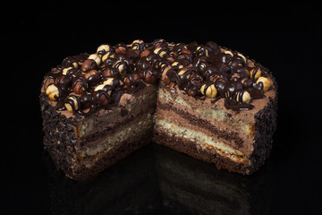 A piece of chocolate cake with hazelnut with white cream on a black background