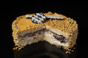 Piece of an ordinary cake covered with peanuts on a black background