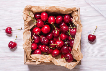Fototapeta na wymiar Lot of cherry in kraft cardboard box on wooden table