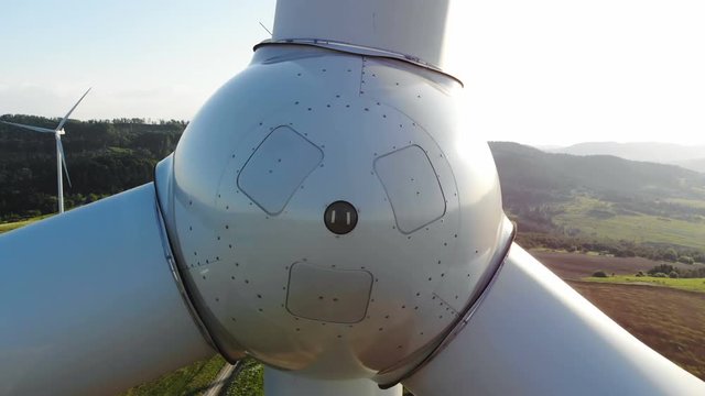 closeup aerial view of wind turbine blades rotating around with beautiful green rural area on sunny background countryside fields sun shining windmill eco farm ecological energy nano-business