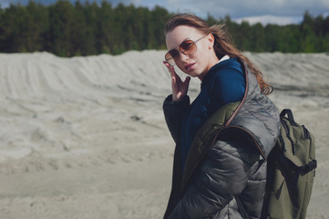 Teen girl loves outdoor activities, she walks through the mountain area dressed in a warm jacket and backpack