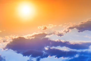 Fototapeta premium Sunset in the orange sky with big sun and blue cloud