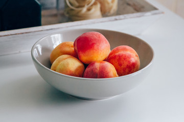 Fresh apricot bowl on the white kitchen table. Local market fruits. Processed filtered image
