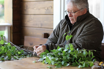 Fototapeta premium Senior man preparing birch broom for the bath. Traditional nothern spa attribute.