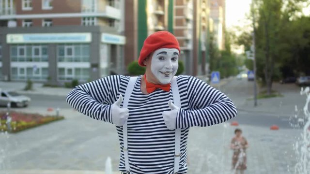 Street mime in red beret show thumbs up to camera