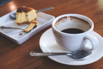 A cup of coffee and a piece of cake on table in cafe