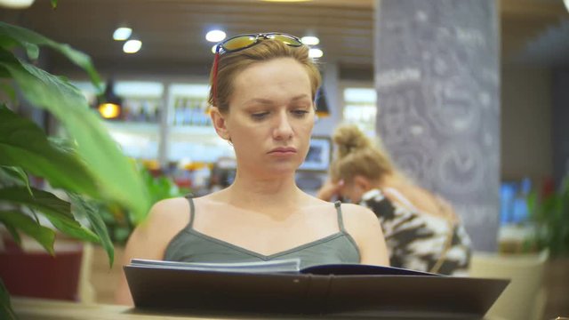 Woman looking at menu in restaurant, turning pages and choosing plates for dinner lunch event dating, 4k, slow motion