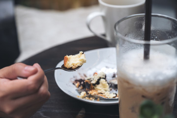 Closeup image of a woman enjoy eating cheese cake and coffee in cafe