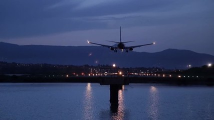 the plane approach and landing at the Kerkira airport at night above the sea - Powered by Adobe