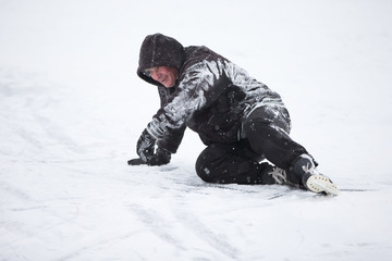 Fototapeta na wymiar The man fell on skates in the snow.An elderly man learns to ride a hockey skate