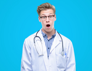 Fototapeta premium Young handsome blond doctor scared in shock with a surprise face, afraid and excited with fear expression
