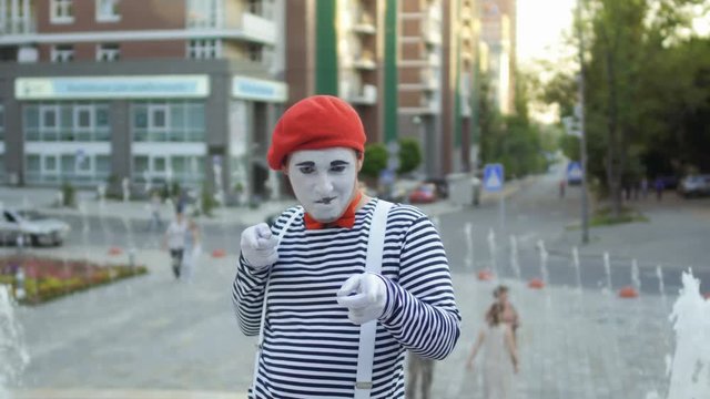 Mime in red beret has fun on camera at fountain background