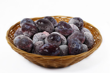 Frozen plums in a basket on a white background