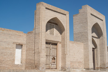 Fototapeta na wymiar An old brick building, with elements of arches. Ancient buildings of medieval Asia. Bukhara, Uzbekistan