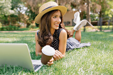 Happy charming pretty lady wears summer bright dress and summer hat studying outside in sunlight...