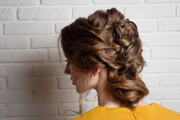 Wedding hairstyle low bun on the head of the brunette rear view. Women's hairstyles.