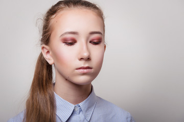 Girl in blue shirt and with bright makeup on closed eyes on gray background close-up.