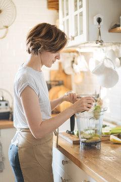 woman putting fruit into blender bowl