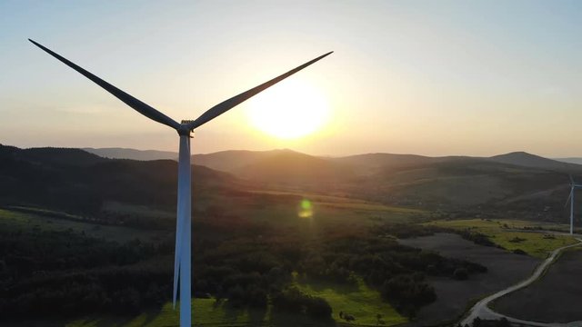 panoramic aerial view of wind turbines with rotating blades on summer fields with beautiful summer fiery sunset on background scenic hillside landscape modern ecosystem renewable energy sources