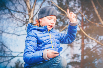 Young red-haired adventurer determines the direction of the wind with the help of a finger