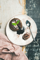Flat-lay of hot chocolate souffle dessert cake with liquid filling and chocolate ice cream over rustic wooden background, top view, copy space