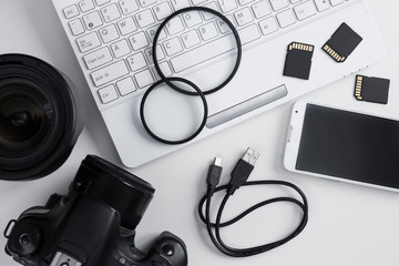 top view of camera, lenses, photography equipment, smart phone and laptop over white