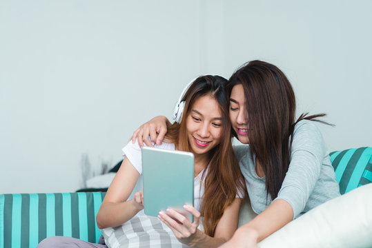 Beautiful young asian women LGBT lesbian happy couple sitting on sofa buying online using tablet in living room at home. LGBT lesbian couple together indoors concept. Spending nice time at home.