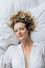 beautiful blond woman in white shirt resting on bed