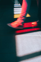 Young man in sneaker walking on the street. Bright light falling down through the colored glass windows on the floor. Cold colors and shadows on the floor