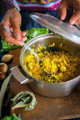 Woman hands tastes pot with cooked bulgur wheat grain porridge with turmeric powder, garlic and spices served for lunch or dinner. Traditional arabic, asian, middle east. Vegan vegetarian healthy food