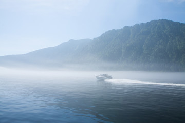 Foggy Teletskoye lake with sailing boat