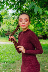 Beautiful young woman with long braid and natural cherry earrings.