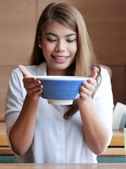 Asian woman holding noodle spicy soup in hands at restaurant.