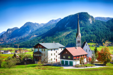 Fototapeta na wymiar Alpine green fields and traditional wooden houses view of the Gosau village at autumn sunny day.