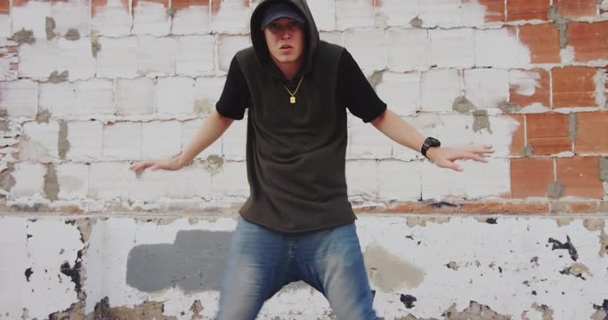 Man freestyle hip hop dancing outside in city  front of brick wall