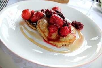 Breakfast pancakes with red berries on a white plate