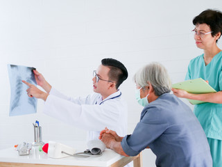 Obraz premium Doctor holding x-ray film in hands present to elderly woman in hospital .Health care concept.